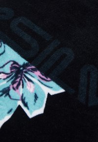 Manta de material polar com um fundo preto e um design floral em turquesa e rosa, além de texto gráfico em cinza.