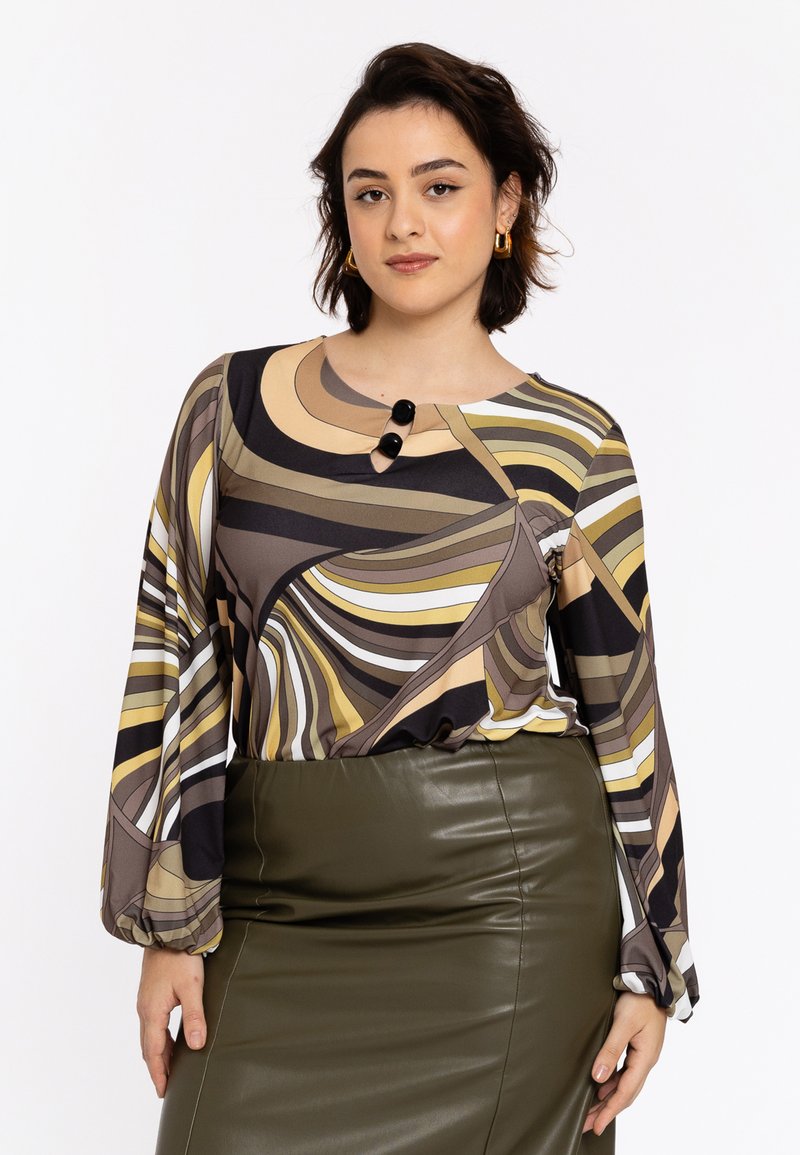 Langærmet bluse med abstrakte bølgemønstre i brun, creme og gul, med en rund halsudskæring og to sorte knapper. Kombineret med en mørkegrøn blyantskirt.