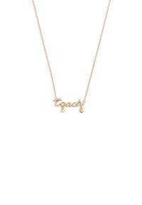 Collier en or avec le mot « Coach » en style cursif, accompagné d'un petit pendentif rond et d'un accent en forme de cœur suspendus en dessous.
