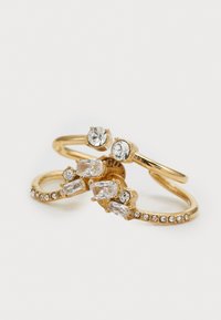 Two gold rings featuring multiple clear rhinestones; one ring with round stones, the other with rectangular stones and a textured band.