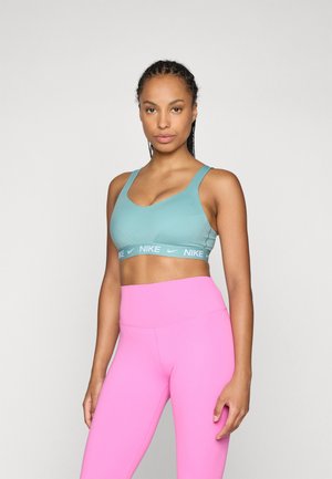 Lyseblå sportsbh med brede stropper og et grått Nike-logo bånd; kombinert med høyt liv rosa leggings. Glatt, elastisk stoff.