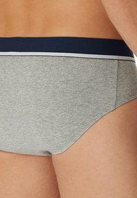 Slip in cotone grigio con vita navy e bordo bianco; design senza cuciture e texture liscia, mostrato da un angolo laterale.