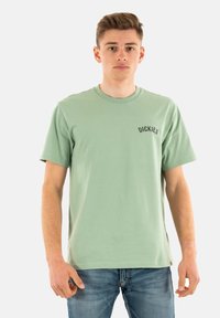 Lichtgroene katoenen T-shirt met ronde hals en korte mouwen. Bevat geborduurd "DICKIES" logo op de linkerborst. Eenvoudig ontwerp.