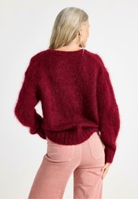 Bordeaux mohair-blandede sweater med løs pasform, ribbet kant og ballonsleeves, parret med lyserøde corduroypants. Tekstureret, varm fremtoning.