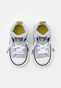 Šedé plátěné tenisky Converse All Star s bílými tkaničkami, gumovými podešvami, černými akcenty a žlutými podšívkami. Obsahují logové nášivky na jazycích.