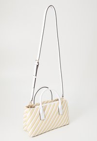Sac rayé jaune et blanc avec des poignées blanches et une sangle détachable. Fabriqué en matériau tissé avec une texture lisse. Forme rectangulaire.