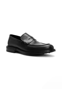 Mocassin en cuir noir avec une finition lisse, présentant un détail de selle cousu, un bout arrondi et une semelle robuste avec un profil de crampons minimal.