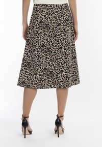 Leopardprint midi-nederdel med en udvidet form, lavet af blødt stof. Sammen med sorte højhælede sandaler med ankelstropper.