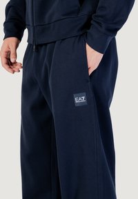 Navyblaue Trainingshose aus weichem Baumwoll-Mix. Mit EA7-Logo-Patch, elastischem Bund und seitlichen Taschen für zusätzlichen Komfort.