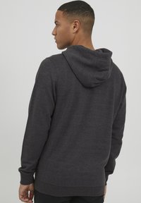 Dark gray hooded sweatshirt with a textured fabric, long sleeves, and a ribbed hem. Features a simple, minimalistic design.