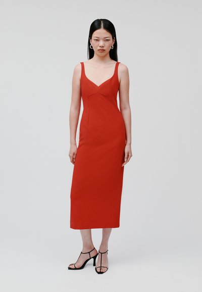 Rode, aansluitende midi-jurk met een V-hals en dunne bandjes. Gladde stof, minimale naden, in combinatie met zwarte bandjeshakken.