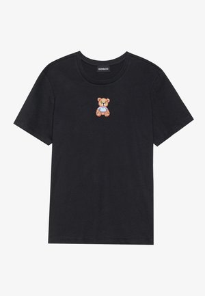 Svart bomullströja med en liten broderad nallebjörn i en blå outfit på bröstet. Rund halsringning och korta ärmar.