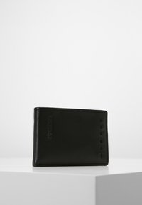 Portafoglio in pelle nera con una texture liscia, forma rettangolare e dettagli cuciti sul lato. Presenta il logo del marchio impressa.