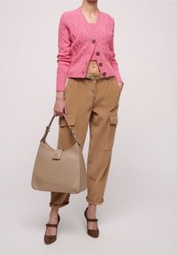 Roze kabelgebreide cardigan met vijf knopen, beige corduroy cargobroek met zakken en een tan schoudertas met een logo en een gladde textuur.