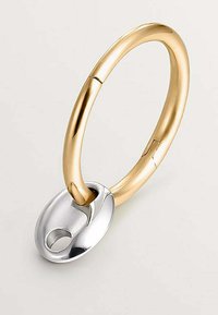 Anillo de metal dorado y plateado con un acabado suave y pulido; cierre en forma ovalada adjunto, que presenta un pequeño agujero y un diseño sin costuras.