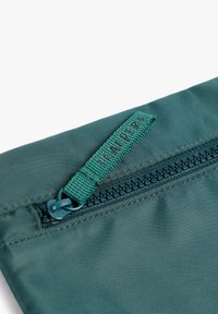 Bolsa de nailon verde azulado con una superficie texturada, que presenta un zipper en contraste y una pestaña de tirón verde etiquetada "CALPERS."