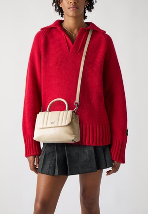 Maglione rosso a maglia con colletto, borsa a tracolla beige trapuntata con manico superiore e una gonna a pieghe nera con motivo a quadretti. Dettagli in metallo marrone semplice.
