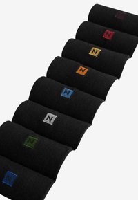 Black socks displayed in a row, each with a square patch featuring the letter "N" in various colors: red, green, blue, orange, yellow, gray.