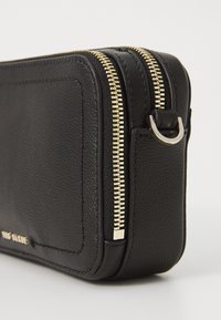 Borsa nera in pelle con zip, superficie testurizzata; presenta una zip e hardware in tonalità oro; forma rettangolare compatta con dettagli di cucitura sottili.