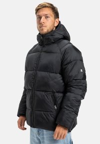 Čierna vyp puffová bunda s kapucňou, so zipsom na prednej strane, horizontálnym prešívaním, bočnými vreckami a logom na rukáve.