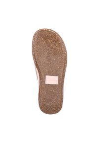 Sole di scarpa marrone con texture e una lieve curvatura, con un'etichetta del marchio di un delicato rosa. I segni di usura visibili indicano l'uso.