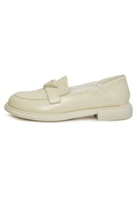 Mocassini in pelle beige con punta rotonda, dettagli cuciti e una fascia decorativa. Tacco basso a blocco e finitura liscia.