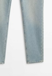 Jean en denim bleu clair avec jambes droites, visible de la moitié de la cuisse à la cheville sur fond blanc.
