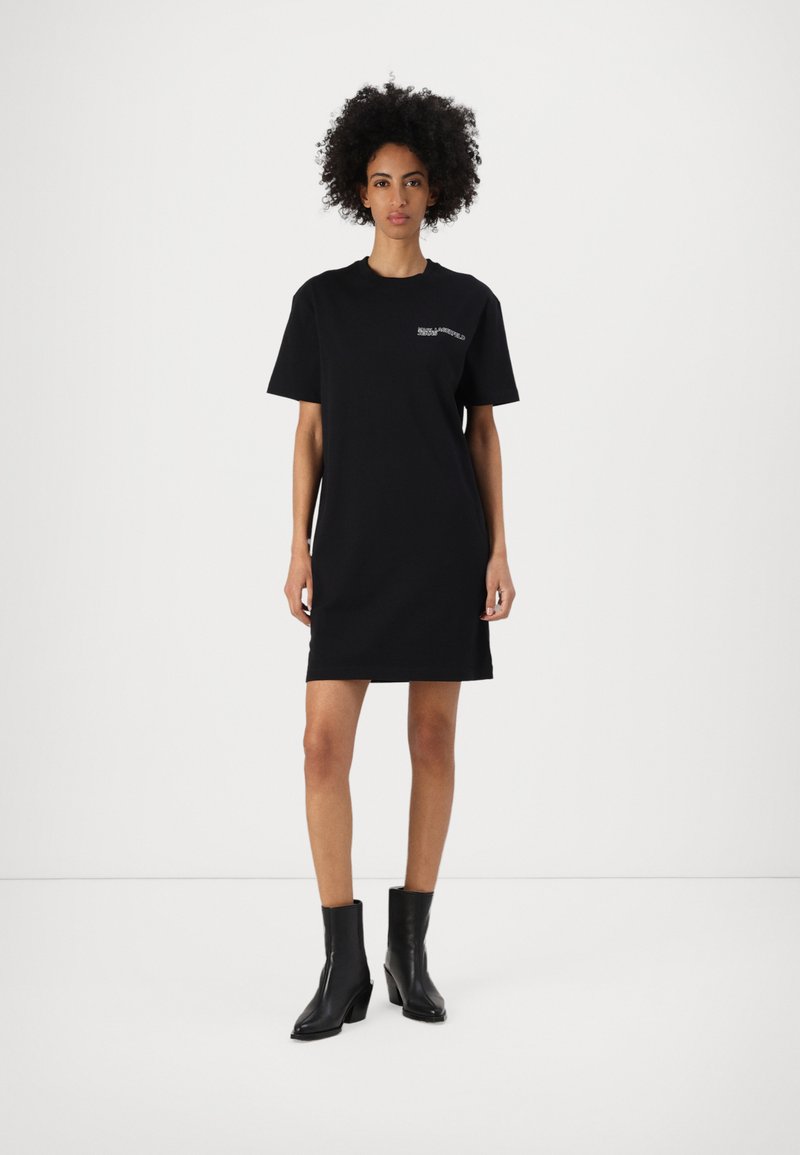 Svart bomulls T-shirt klänning med korta ärmar, rundad halsringning och rak passform. Har en minimal vit logotyp på vänster bröst.