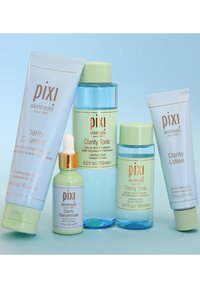 Cinque prodotti per la cura della pelle di Pixi: Clarity Cleanser (tubo blu), Clarity Tonic (bottiglia trasparente, tappo verde), Clarity Concentrate (contagocce verde), Clarity Lotion (tubo bianco).