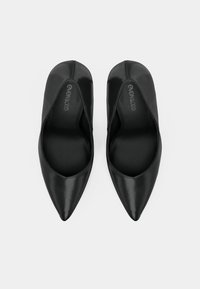 Musta patentoitu nahkaiset kärjestä teräväkärkiset ballerinat, joissa on sileä pinta ja virtaviivainen muotoilu, matala leikkaus vampissa ja minimalistinen tyyli.