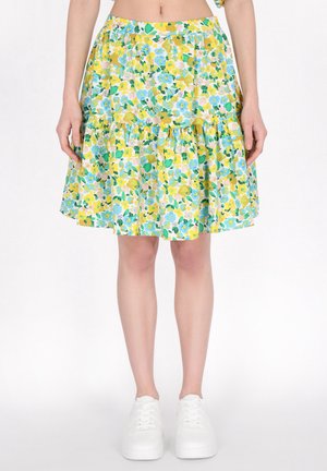 Gonna a stampa floreale con design a strati, nei colori giallo, blu e verde. Realizzata in tessuto leggero, abbinata a sneakers bianche.