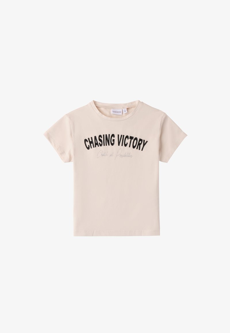 Camiseta de manga corta de color beige hecha de algodón, con un texto en negrita de color negro "PERSIGUIENDO LA VICTORIA" en la parte delantera y un cuello redondo.