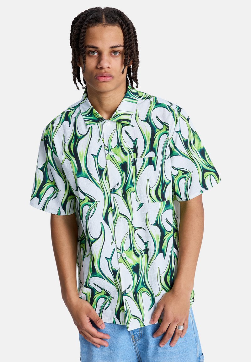 Κοντομάνικο πουκάμισο από λευκό ύφασμα με πράσινα και σκούρα μπλε αφηρημένα μοτίβα. Διαθέτει τσέπη στο στήθος και γιακά στο λαιμό.