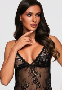 Czarny koronkowy bodysuit z kwiatowymi wzorami i przezroczystym materiałem, z głębokim dekoltem w kształcie litery V oraz delikatnymi akcentami wykończeniowymi. Elegancki i kobiecy design.