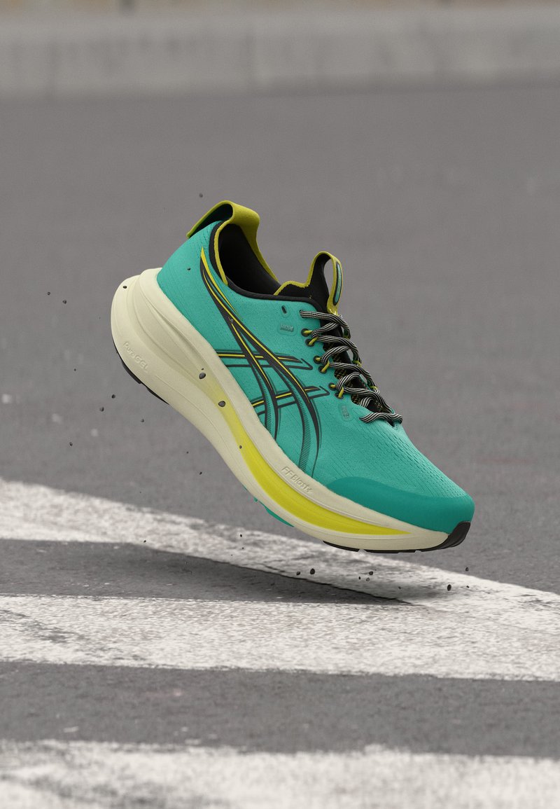 Blågrønn og gul løpesko med svarte lisser svever over en grå brosteinsbelagt overflate med hvite veimerkinger.