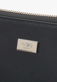 Černá kožená taštička se stříbrnou destičkou s logem "estro BEAUTY". Obsahuje kovový zip a hladký povrch. Jednoduchý obdélníkový design.