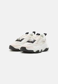 Chunky sneakers with a white mesh upper, black accents, and textured grey rubber sole. Features laces and a pull tab at the heel.