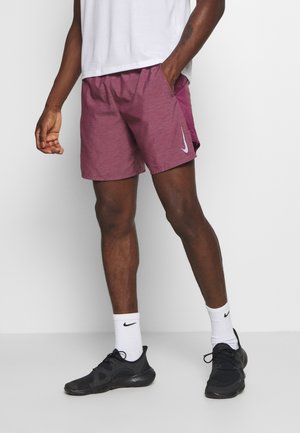 Bordowe szorty sportowe o heatherowanej fakturze, z białym logo Nike na dolnej krawędzi, zestawione z czarnymi sneakersami i białymi skarpetami w paski.