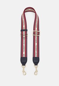 Regulowany pasek Tommy Hilfiger z granatowym splotem, czerwonymi i białymi paskami, złotymi akcentami oraz logo biegnącym wzdłuż całej długości.