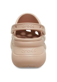 Crocs rosa chiaro con retro chiuso, cinturino regolabile e superficie texturizzata. Presenta il nome del marchio impresso sul tallone e sul cinturino.
