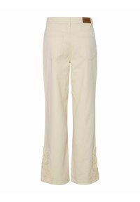 Pantalones de pierna ancha beige con una tela suave, que presentan acentos florales bordados en los dobladillos y bolsillos parchados en la parte trasera.