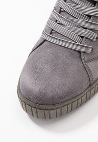 Baskets en daim gris avec un bout arrondi, lacets gris texturés et semelle en caoutchouc rainurée pour une meilleure adhérence. Sans logo visible.