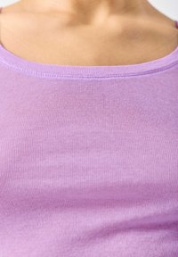 Fioletowy prążkowany top na ramiączkach z okrągłym dekoltem. Tkanina wygląda na miękką i teksturowaną, z cienkimi ramiączkami i subtelnymi detalami przeszyć.