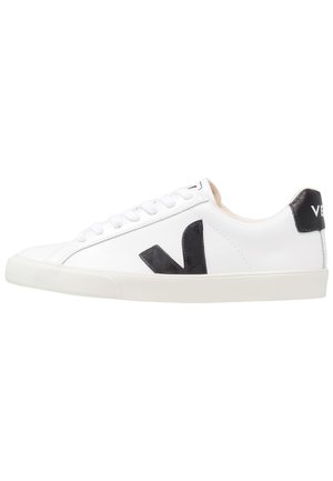 White low-top sneaker with black "V" logo on the side and black heel tab, white laces, and off-white rubber sole.