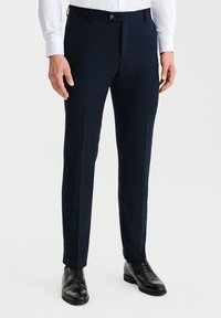 Granatowe spodnie garniturowe wykonane z gładkiego materiału, z fasonem slim fit, płaskim przodem i standardowym pasem z zapięciem na guzik.