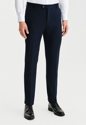 Granatowe spodnie garniturowe wykonane z gładkiego materiału, z fasonem slim fit, płaskim przodem i standardowym pasem z zapięciem na guzik.