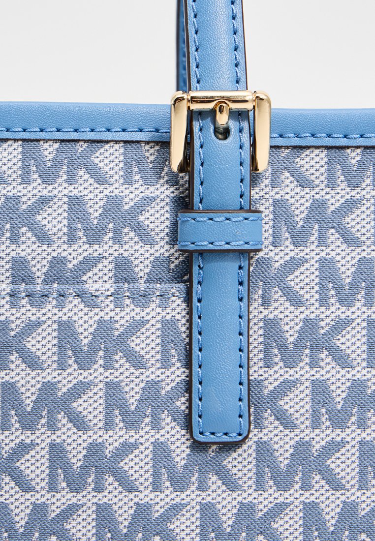 Borsa a tracolla blu con motivo, realizzata in un tessuto texturizzato con il logo "MK", dettagli in pelle e hardware dorato per la chiusura.