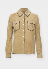 Giacca scamosciata beige con chiusura a bottoni, due tasche sul petto con borchie, rifiniture in contrasto nere e bottoni a scatto in argento. Maniche lunghe.