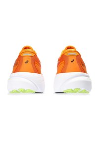 Baskets de sport orange avec une tige en maille texturée, une grande semelle intermédiaire blanche et des accents de semelle extérieure verte. Comprend des détails réfléchissants au niveau du talon.