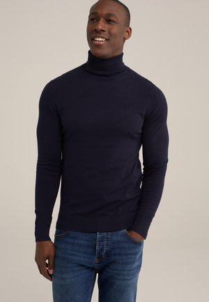 Marineblauer Rollkragenpullover aus glatt gestricktem Stoff, mit langen Ärmeln und gerippten Bündchen, kombiniert mit klassischen blauen Jeans.